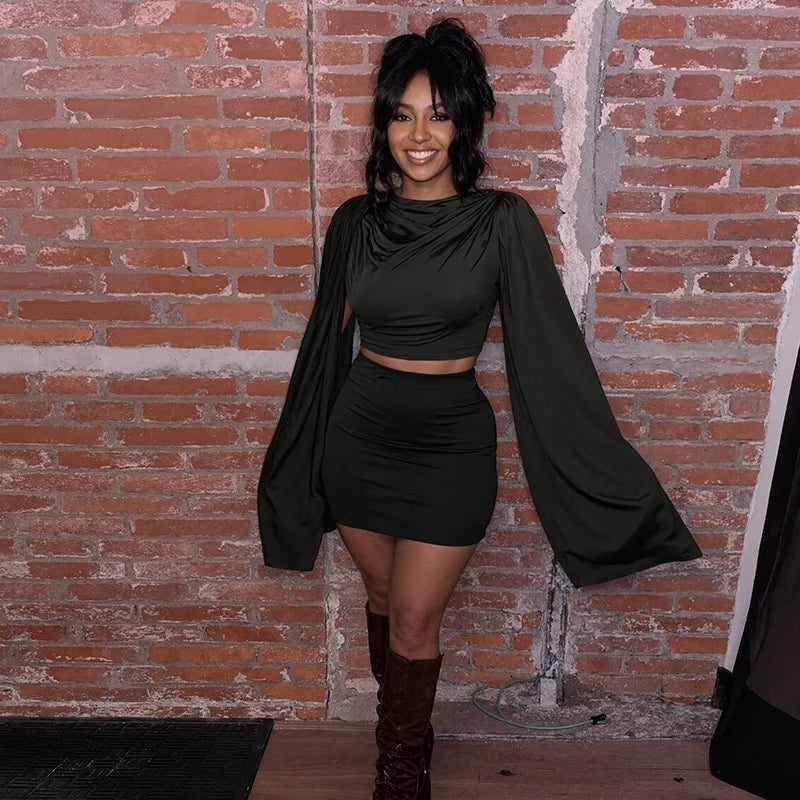 Woman in a black outfit standing against a brick wall
