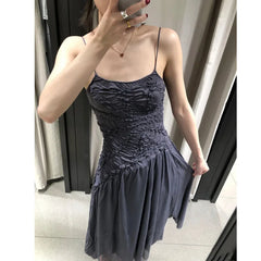 Model adjusting the hem of a ruched bodice asymmetrical hem spaghetti strap dress