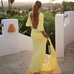 Woman in a yellow dress standing on a balcony with a scenic background