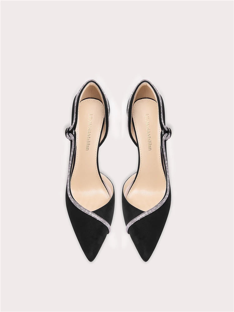 Black pointed-toe shoes with thin straps on a light gray background