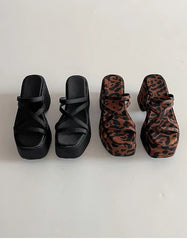 Two pairs of platform sandals, one black and one with leopard print, on a white background.