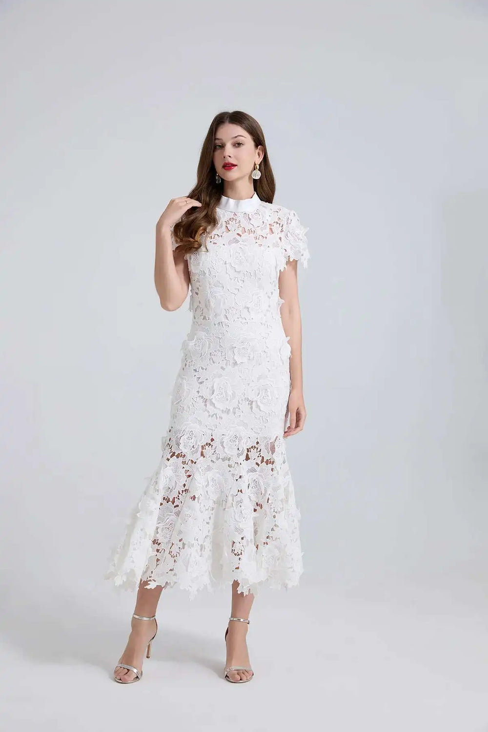 Woman wearing a white lace dress against a plain background