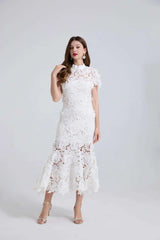 Woman wearing a white lace dress against a plain background