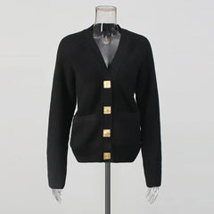 Black cardigan with gold buttons on a mannequin against a gray background