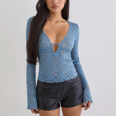Woman wearing a blue lace long-sleeve top and black shorts on a light gray background