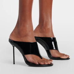 Black patent thong heels on a model's feet.