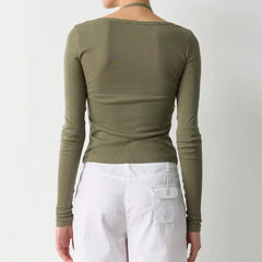 Person wearing an olive green long-sleeve top and white pants on a plain background