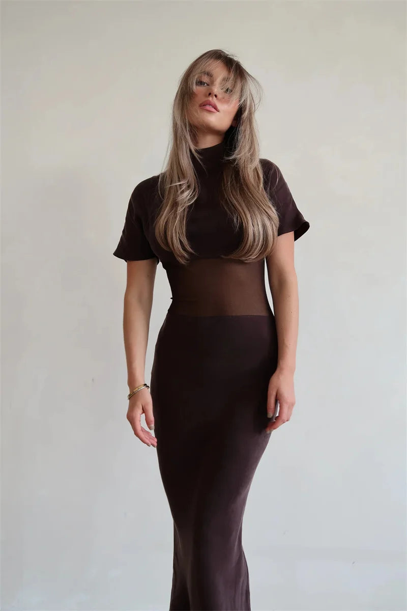 Woman wearing a brown outfit with sheer panels against a plain background