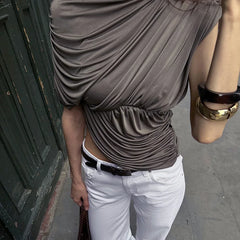 Person wearing a brown sleeveless top and white pants with a blurred background