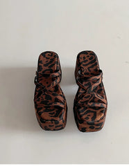 Pair of leopard print sandals on a white background