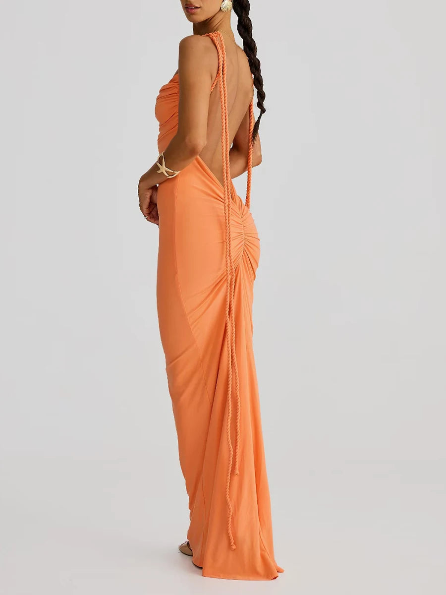 Woman wearing an orange evening gown with a backless design on a light gray background