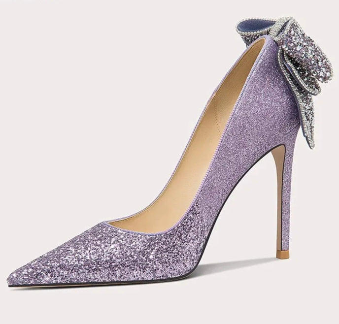 Purple glitter high-heeled shoe with a decorative bow on a white background