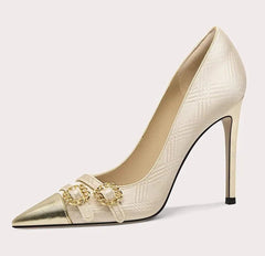 Beige high-heeled shoe with gold embellishments on a light gray background