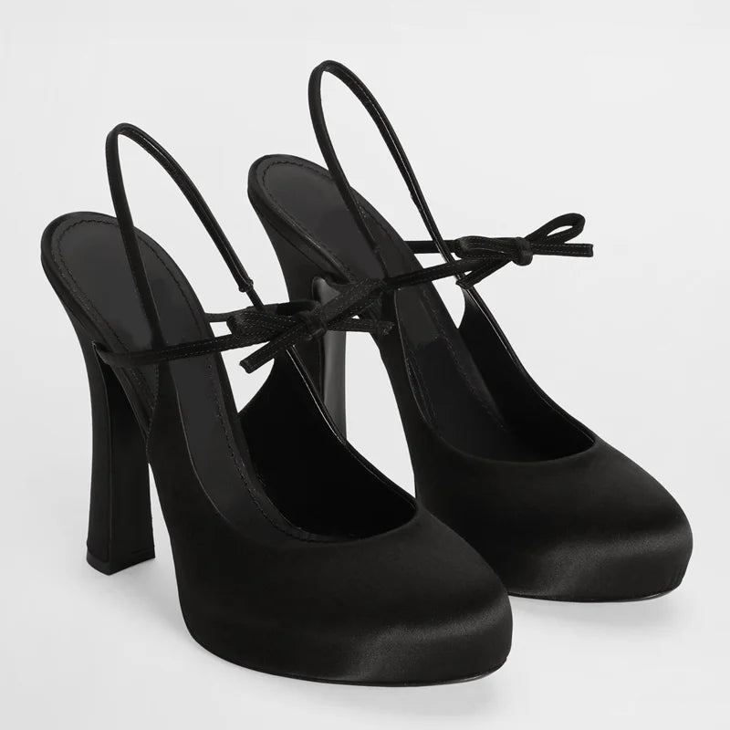 Black satin slingback platform pumps with ribbon tie detail.