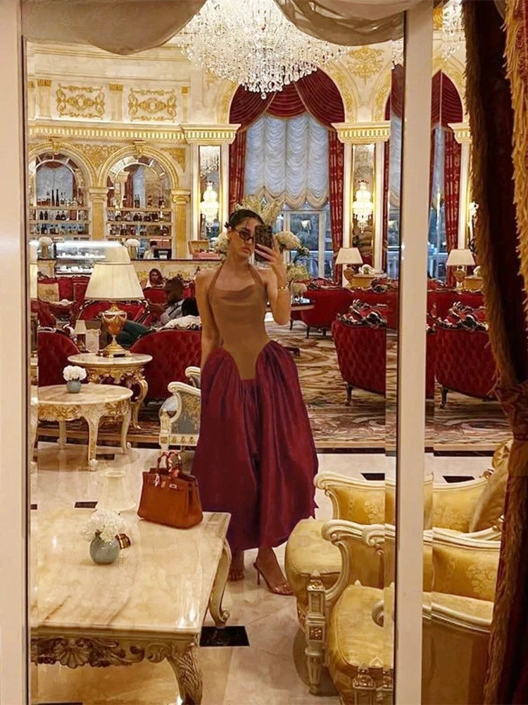 Woman taking a mirror selfie in an opulent room with red chairs and chandeliers.