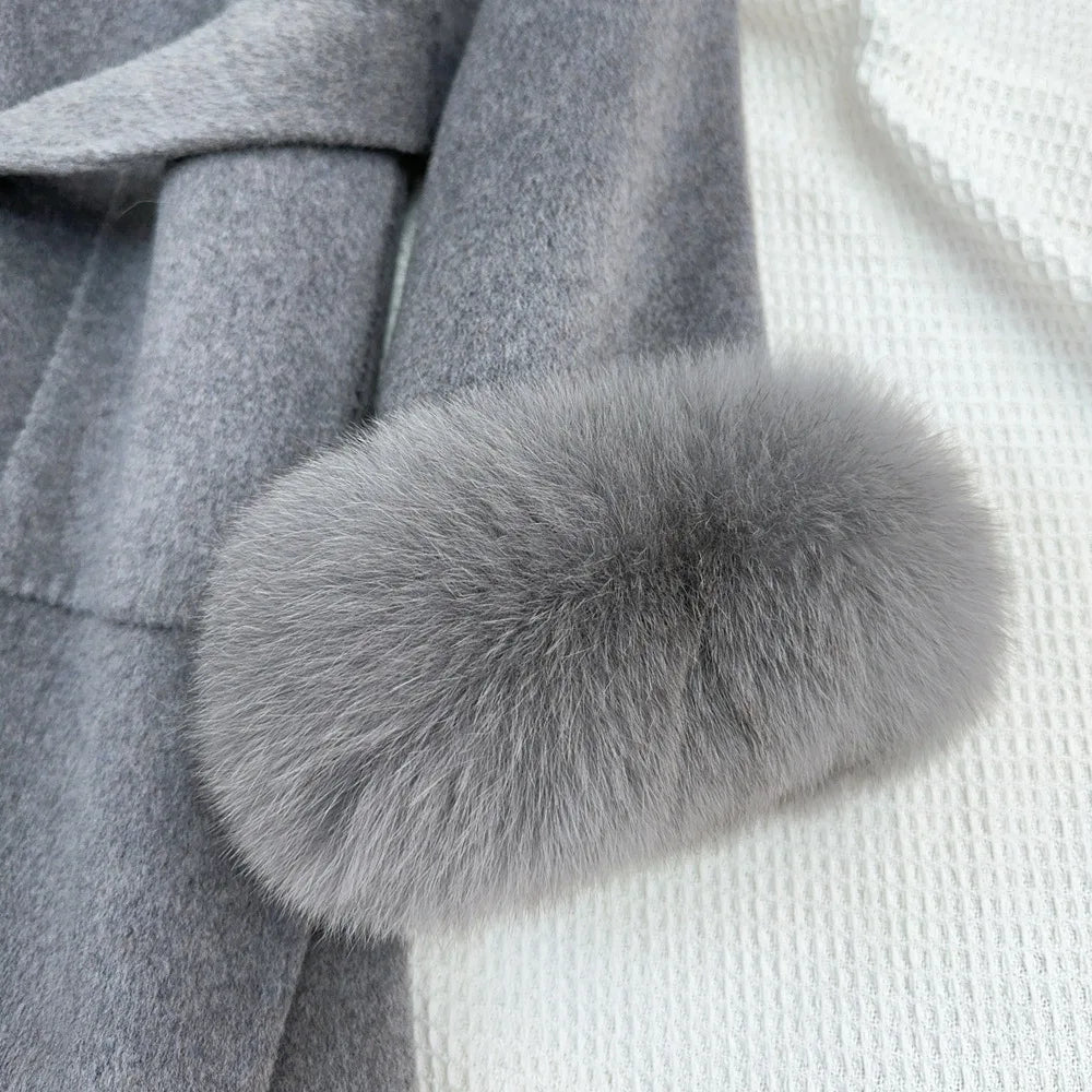 Gray fur pom-pom on a gray coat against a white background