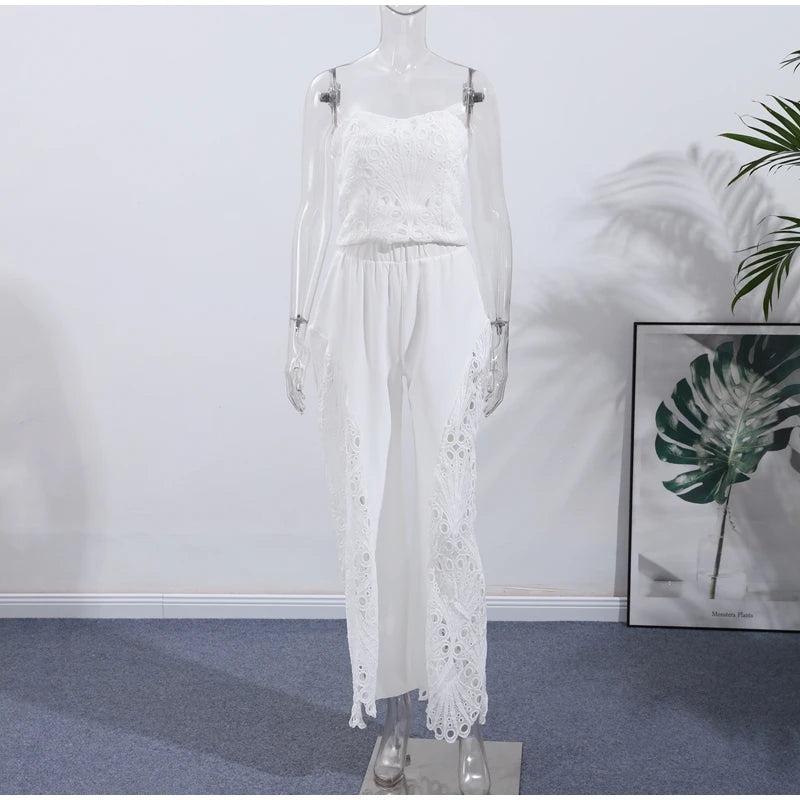 White lace dress on a mannequin against a white wall with a plant in the corner.