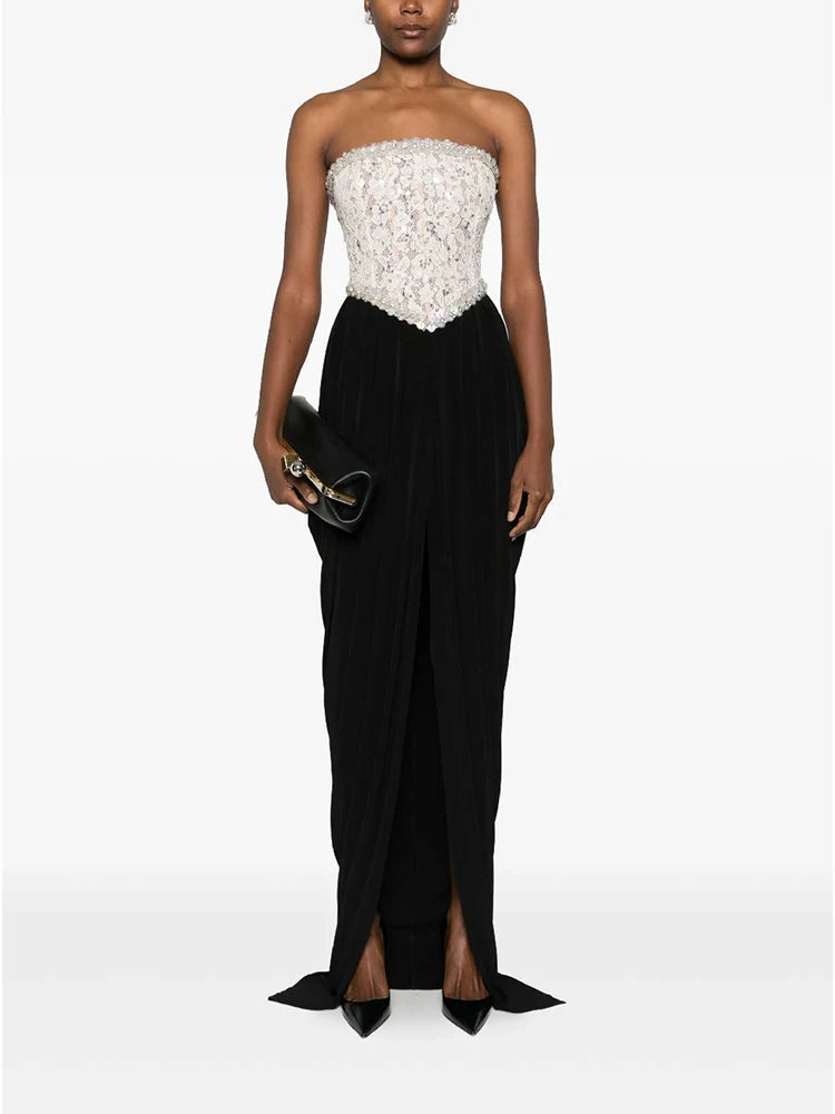 Woman wearing a strapless white lace top and black evening gown with a white background