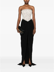 Woman wearing a strapless white lace top and black evening gown with a white background