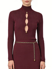 Maroon ribbed long-sleeve top with gold embellishments and a chain belt on a white background