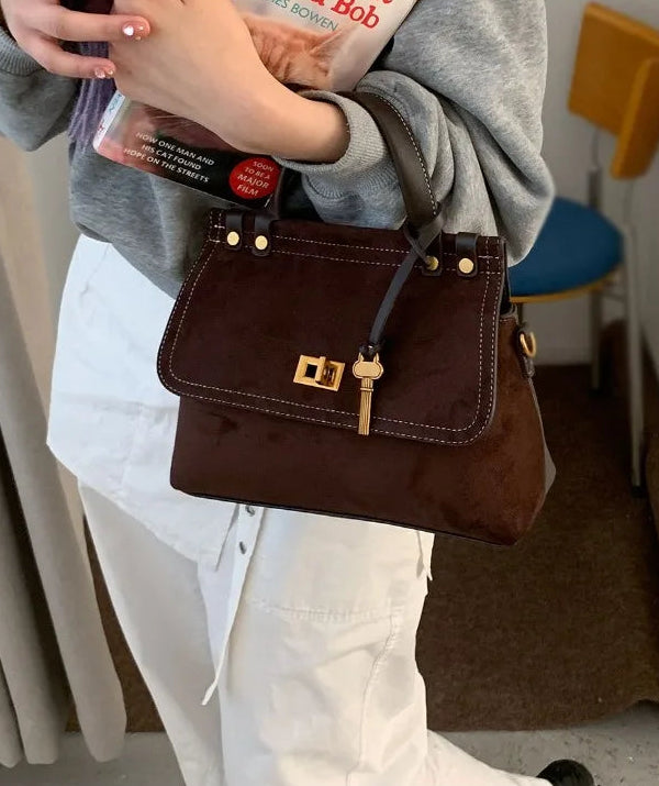 Brown handbag held by a person in a casual setting