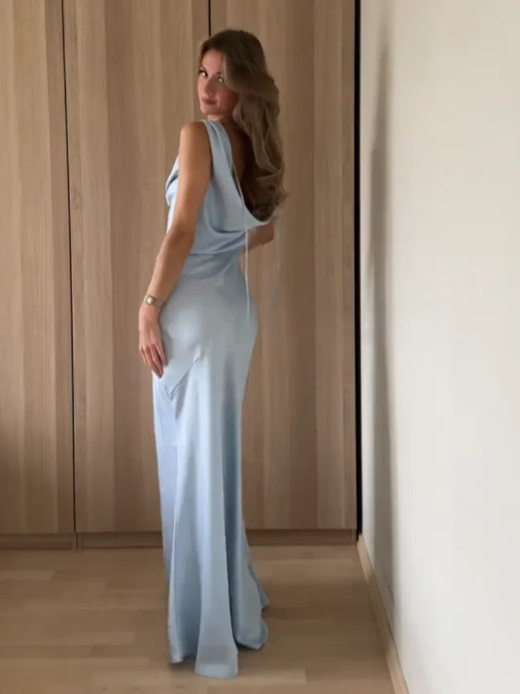 Woman in a light blue dress standing in a room with wooden paneling.