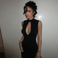 Woman wearing a black dress with a plunging neckline against a plain background