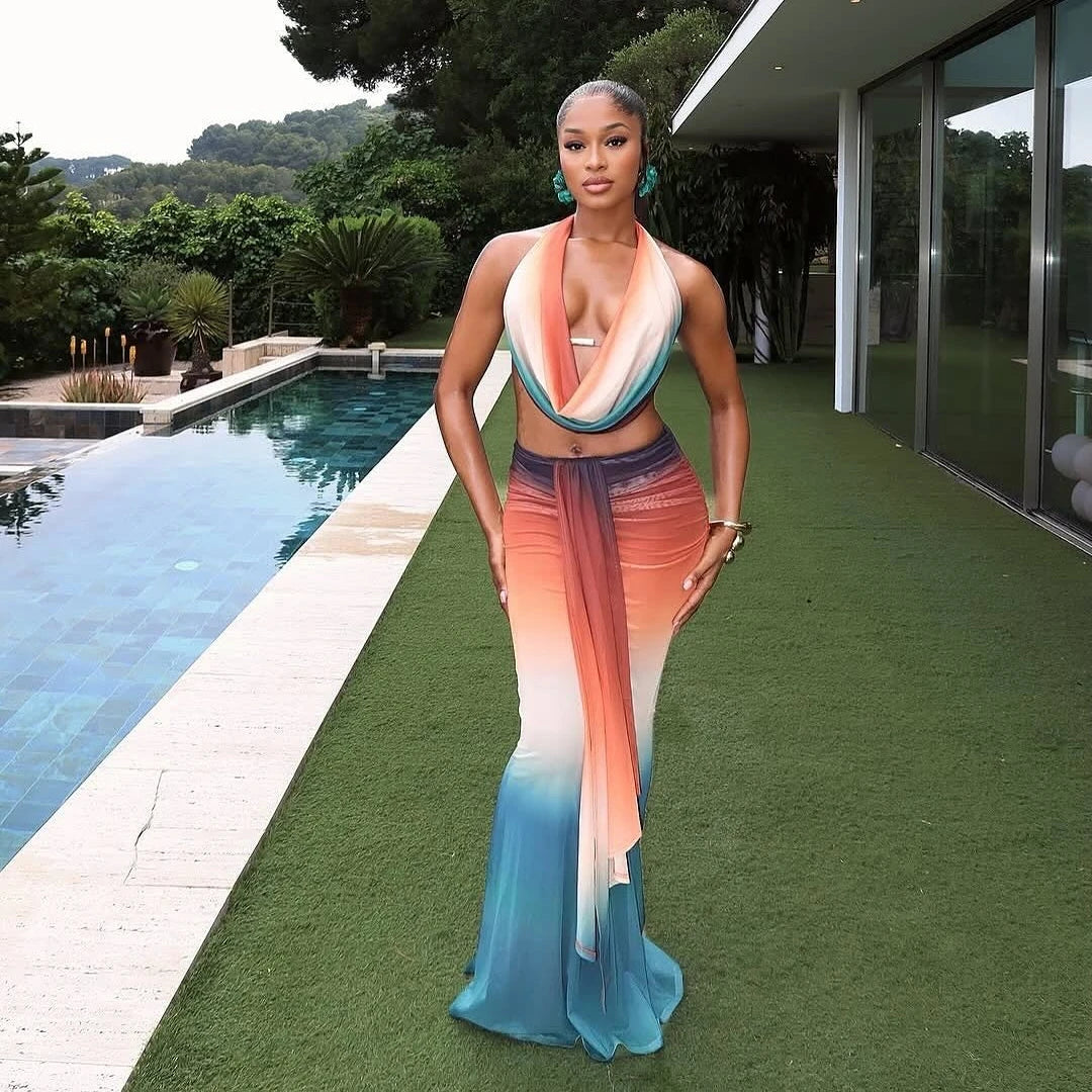Woman in a colorful dress standing by a pool with greenery in the background