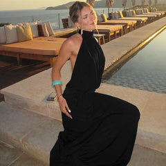 Woman in a black dress sitting by a poolside with a scenic background
