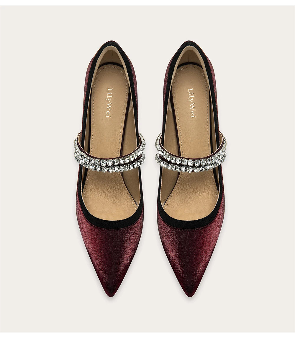 Pair of maroon high-heeled shoes with silver ankle straps on a light beige background