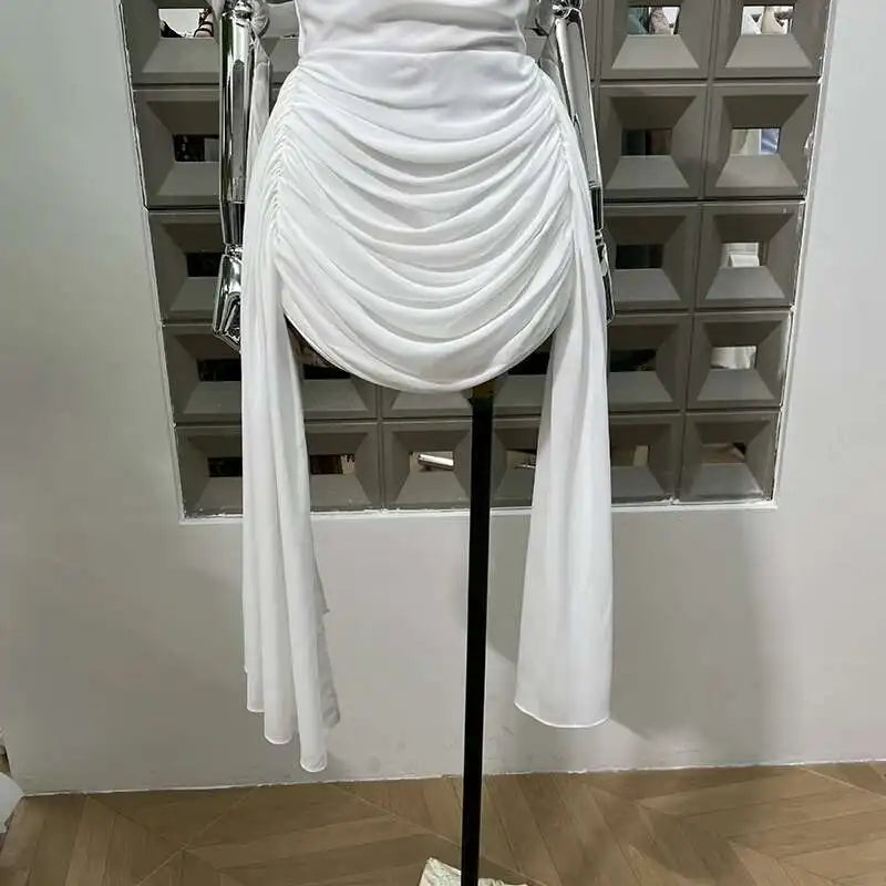 White evening gown on a mannequin against a geometric-patterned wall.