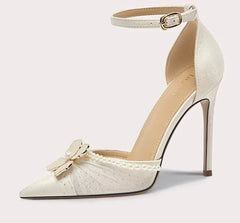 White high-heeled shoe with decorative bow and pearls on a light gray background