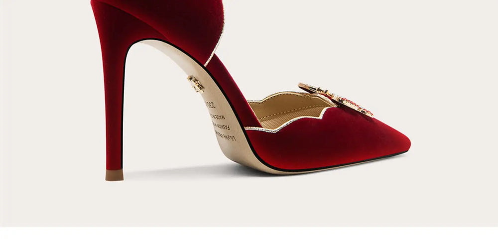 Red high-heeled shoe with gold accents on a light gray background