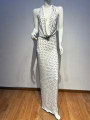 Mannequin wearing a long, elegant dress with a halter neck design on a wooden floor.