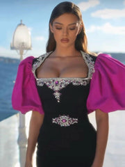 Woman wearing a black dress with pink sleeves and intricate embellishments on a boat.