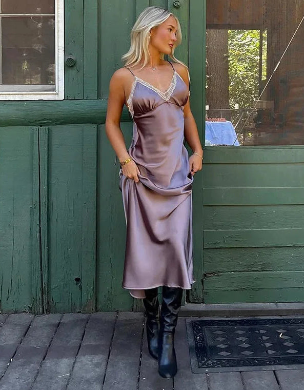 Woman in a satin slip dress standing in front of a green wooden door.