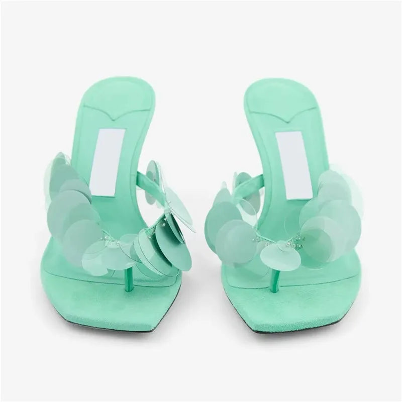Front view of aqua green heeled thong sandals with sequin floral detail.
