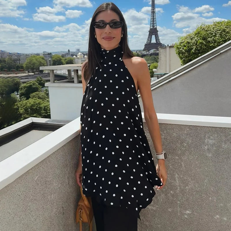 Woman in a black polka dot dress standing on a rooftop with the Eiffel Tower in the background.