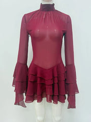Maroon dress with sheer long sleeves and ruffled skirt on a white mannequin against a white background