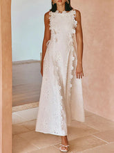 Woman wearing a white lace dress standing against a light pink wall.