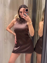 Woman wearing a brown dress taking a mirror selfie.