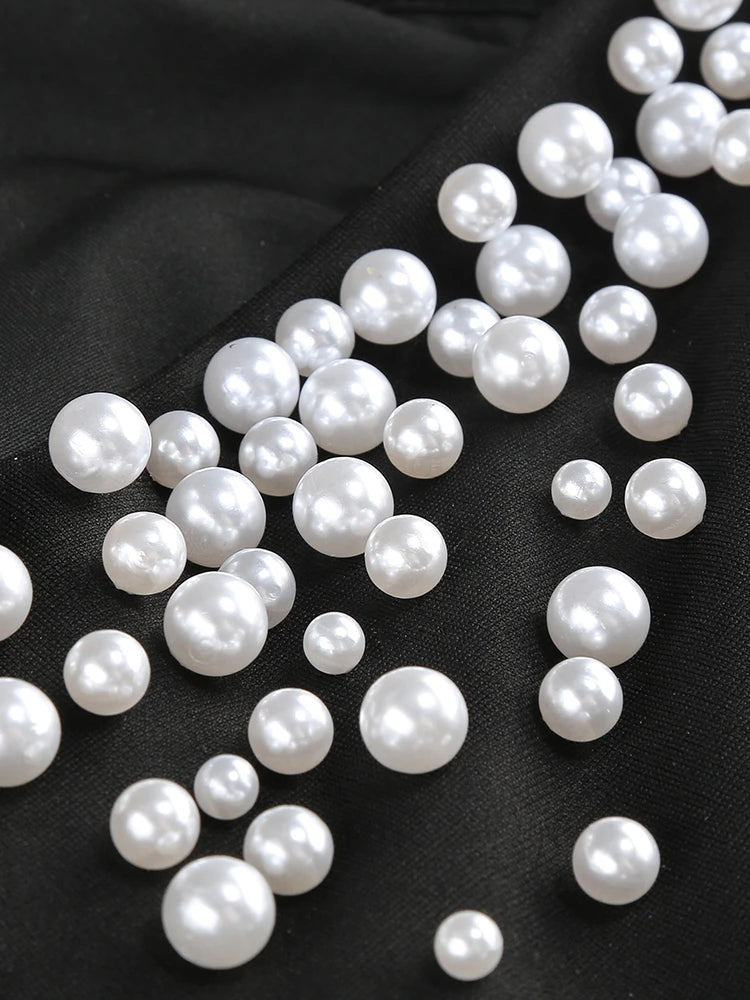 White pearls scattered on a black fabric background
