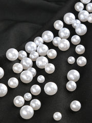 White pearls scattered on a black fabric background