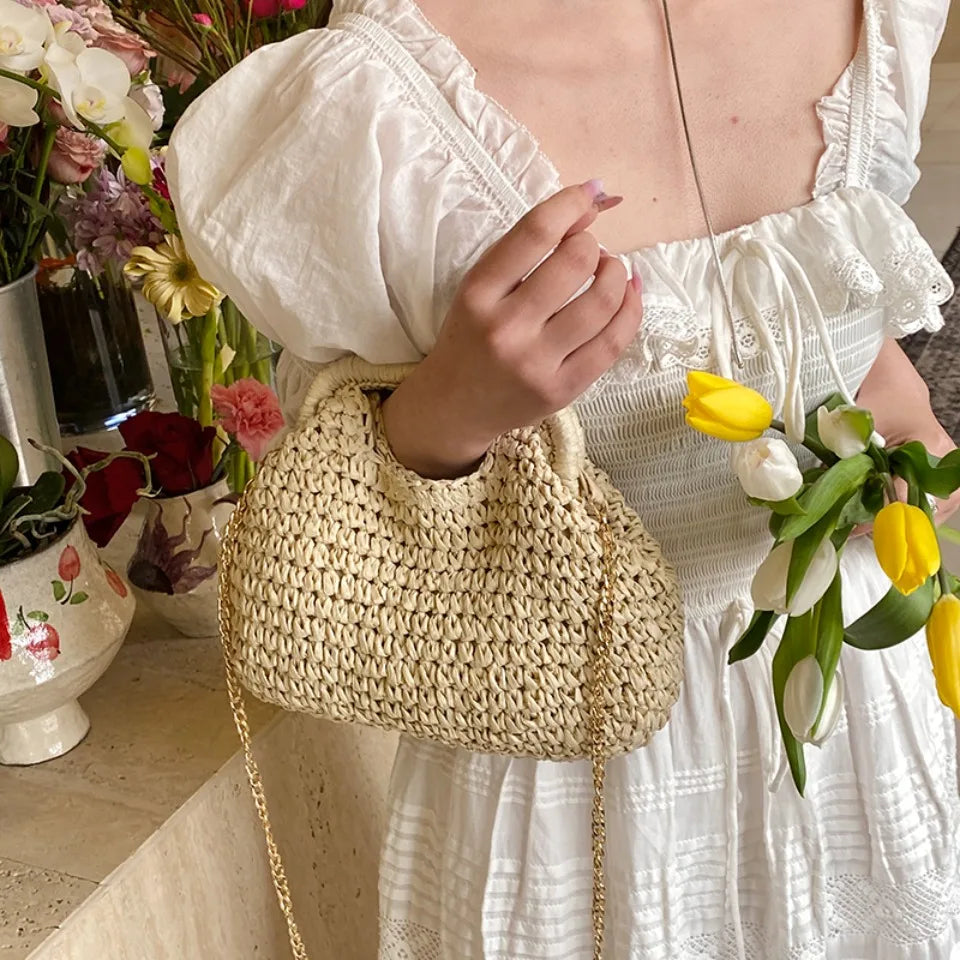 Person holding a woven handbag with flowers in the background