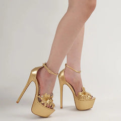 Gold high-heeled shoes with floral designs on a neutral background