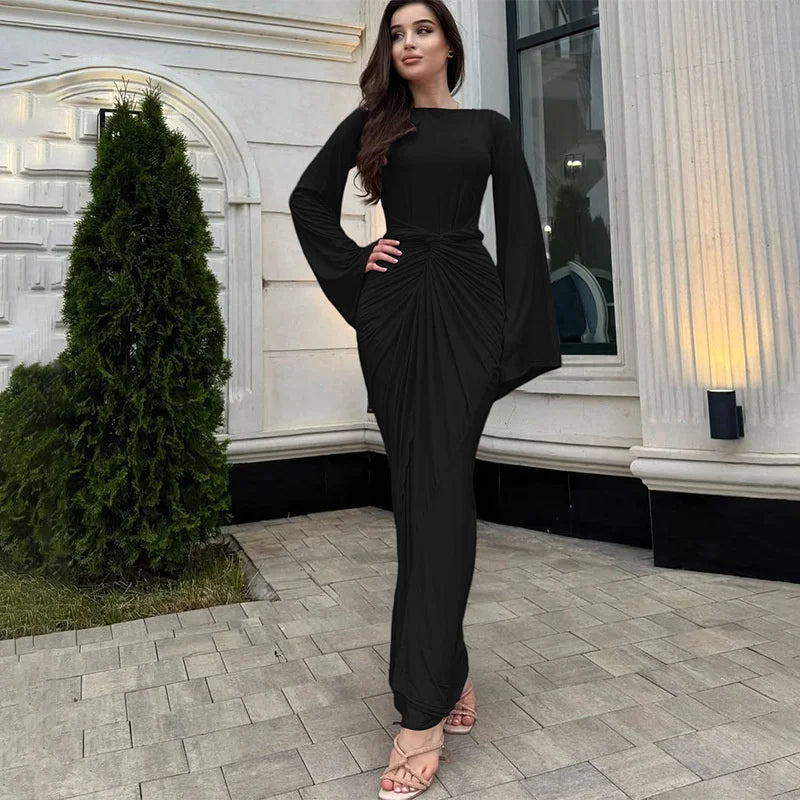 Woman in a black dress standing in front of a building entrance.