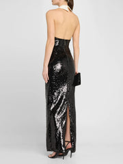 Black sequin halter neck gown with a slit on a white background