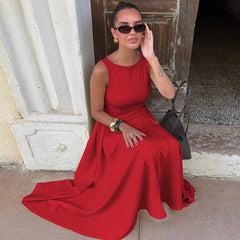 Woman in a red dress sitting against a stone wall.