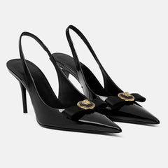 Black pointed toe slingback heels with a bow detail and gold metal accent