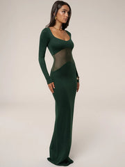 Woman wearing a green evening gown with sheer panels on a plain background